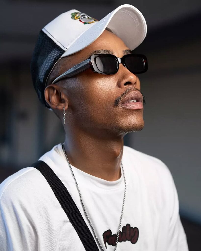 Stylish man wearing sunglasses and a baseball cap with a "Family" t-shirt on a city street.